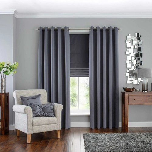 gray window curtains hang elegantly on a wall, framing a window with a matching Roman shade