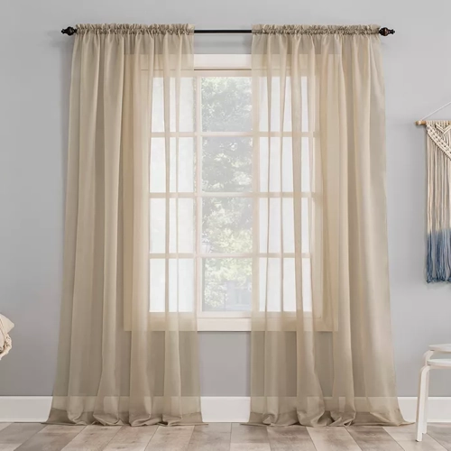 pair of sheer Window curtains hanging on a window, allowing soft light to filter through